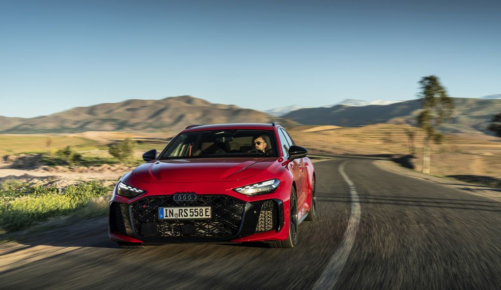 The Audi RS 5 Avant in Progressiv red on a winding mountain road – sporty driving dynamics in demanding surroundings.